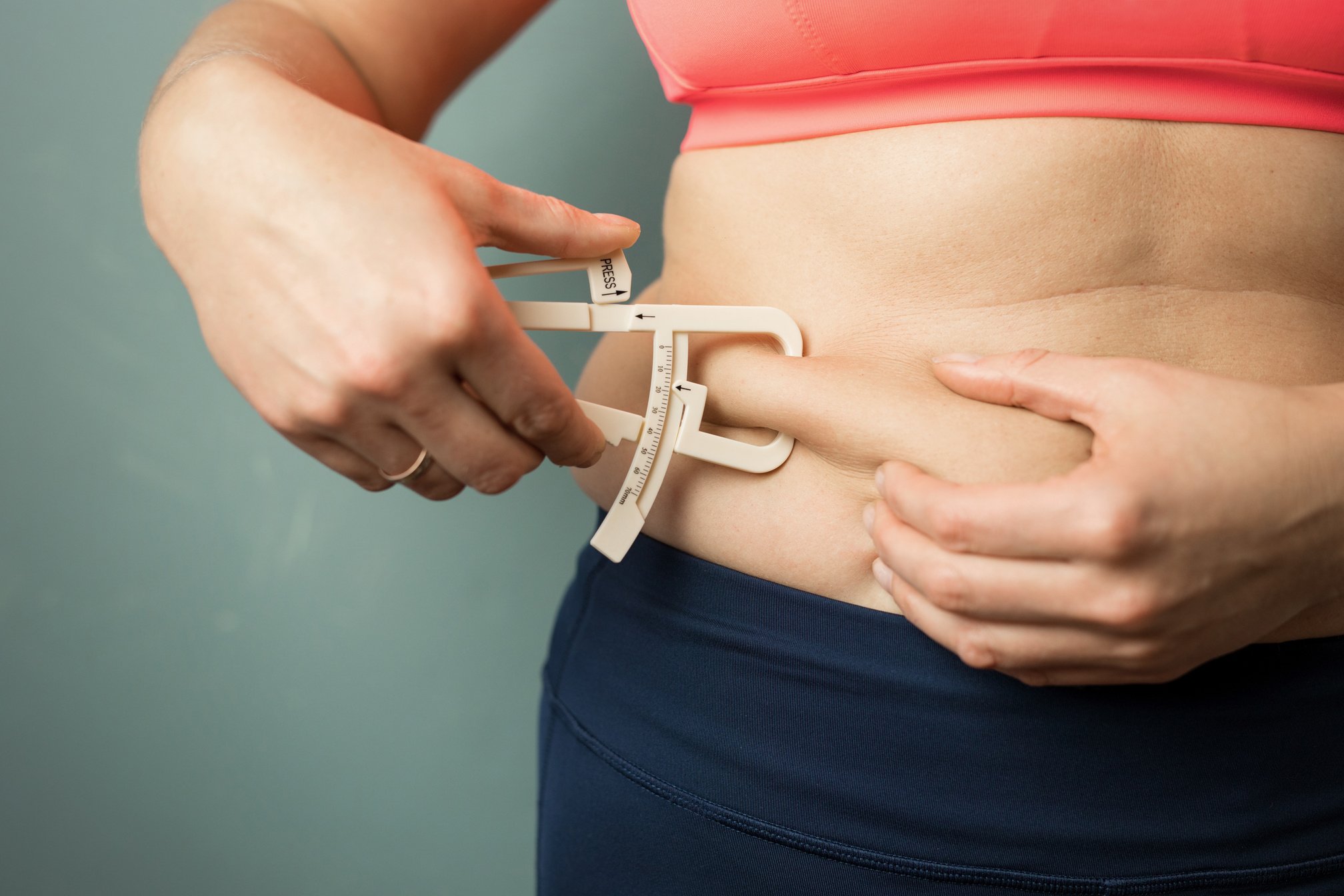 Woman Measuring Her Body Skin Fat with Fat Caliper